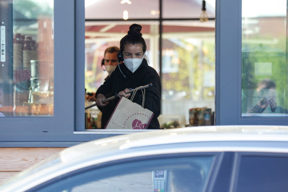  Staff are seen wearing facemasks and passing drinks on a long stick to a queue of drivers as Costa Coffee reopened in Mansfield on April 24