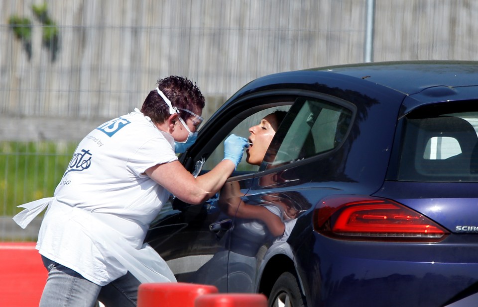  A medical worker conducts a covid-19 check-up at a drive-thru testing site in Chessington, London