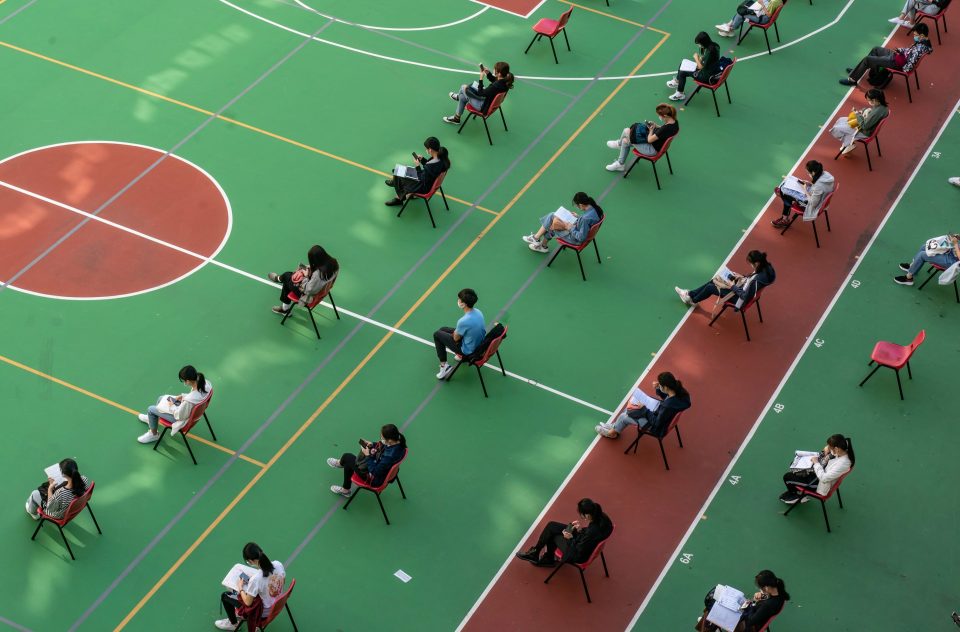  Students sit spread apart in a school gym in Hong Kong