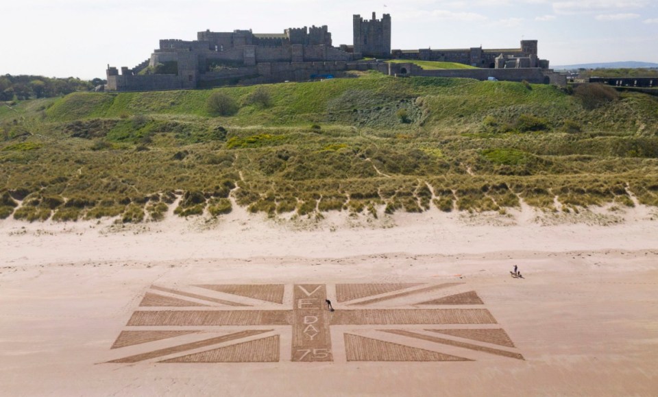  Andrew Heeley, 56, a maintenance manager at Bamburgh Castle, draws a giant Union flag on the beach beneath the castle in Northumberland