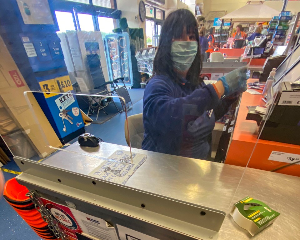  A shopkeeper wearing a mask and gloves for protection in the Range in Worthing