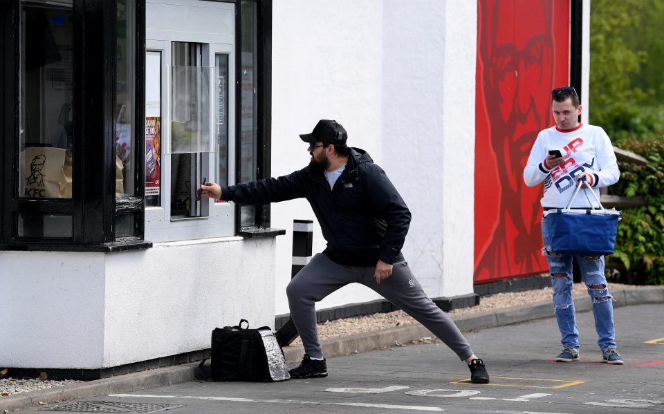  A man tries to keep his distance while showing his phone to the staff as he picks up KFC on May 2