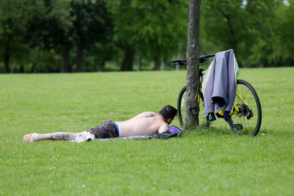  A man sunbathes in Finsbury Park, London