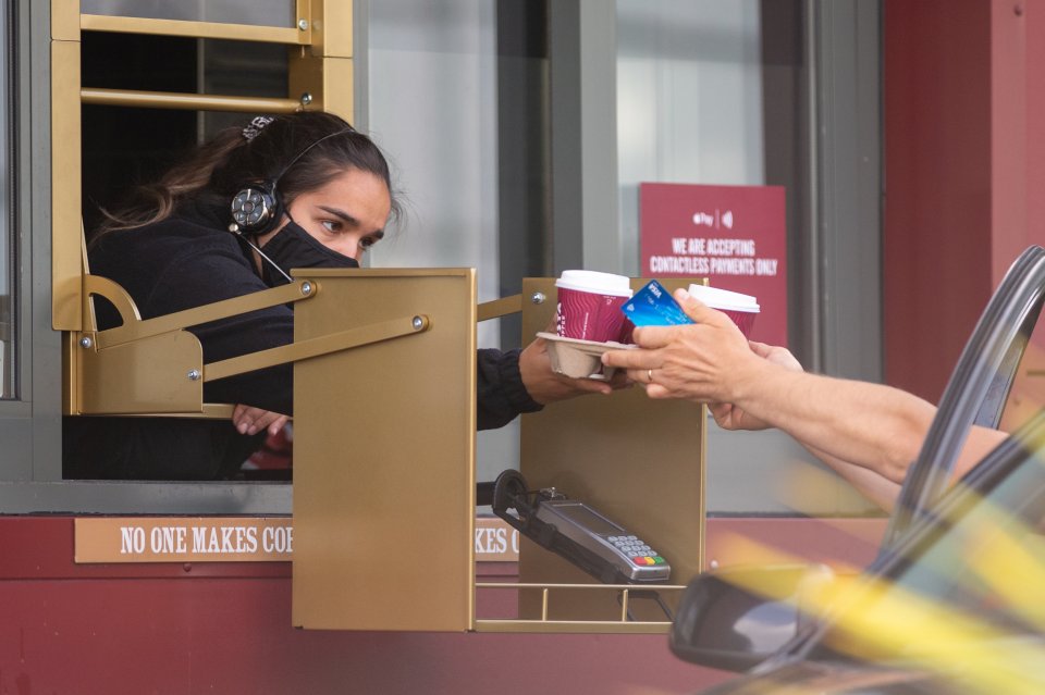  This barista in Croydon, South London wore a face mask for protection as she served a customer