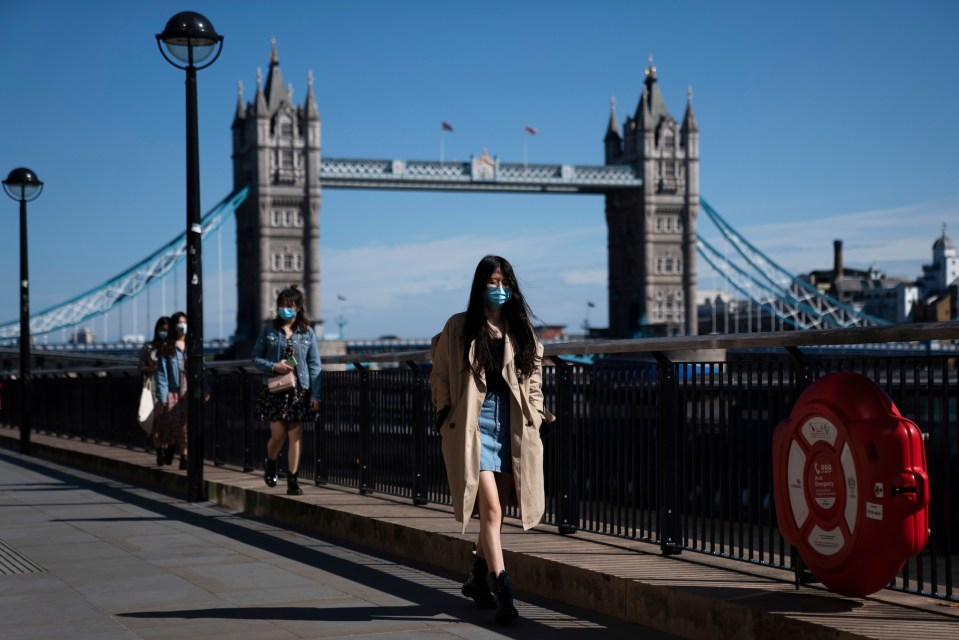  A woman in a face mask walks past Tower Bridge in London