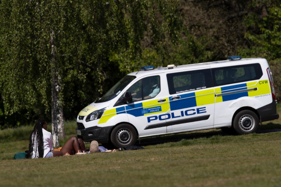  Police drive past sunbathers as the patrol Greenwich Park