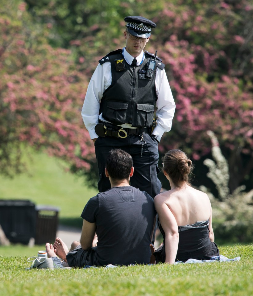  Police officers talk to members of the public lying down on Primrose Hill in North London during lockdown