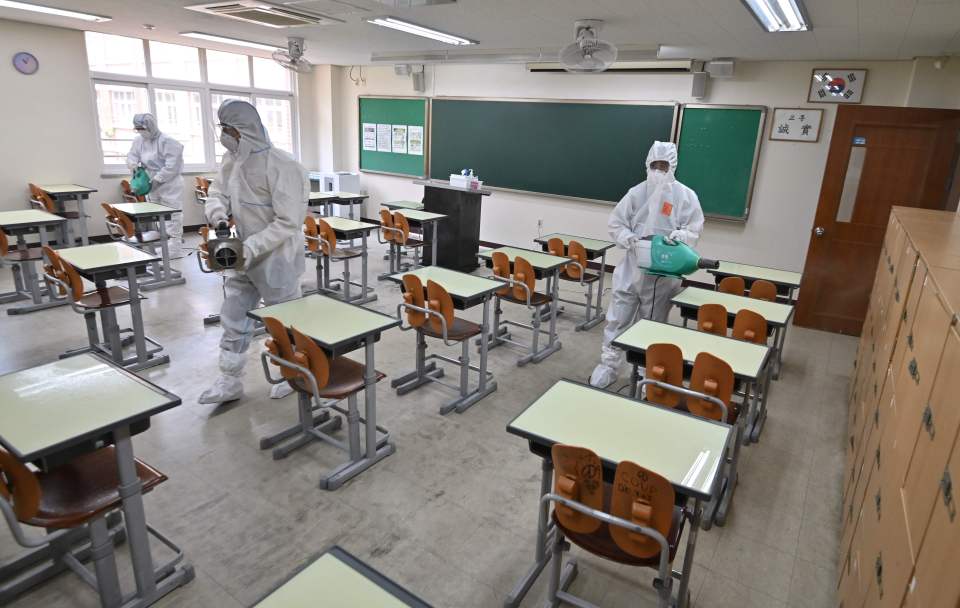  Health officials wearing protective gear spray disinfectant in a classroom at a high school in Seoul, South Korea