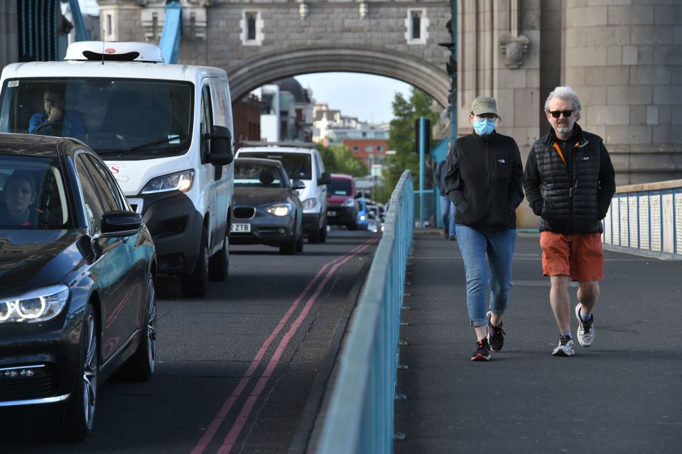  Pedestrians pass the heavy traffic as they walk over Tower Bridge in London