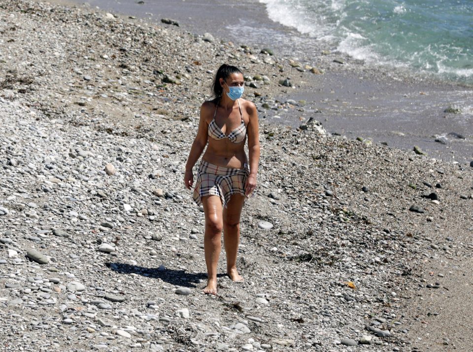  A woman wearing a protective mask walks at Naxos beach as Italy eases restrictions