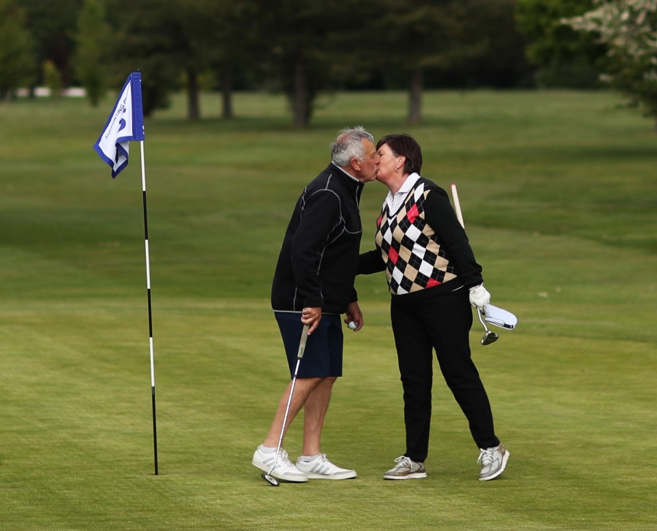  A couple share a kiss on the 18th green after finishing their round of golf