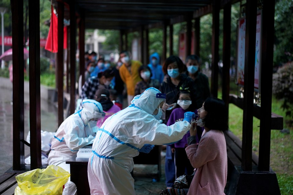 A medical worker pictured in a protective suit conducts a nucleic acid testing for a child at a residential compound in Wuhan