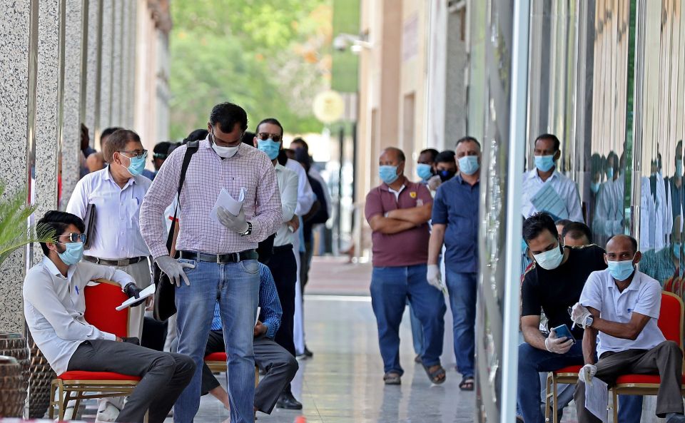  Men in face masks wait in a queue in the Qatar capital Doha