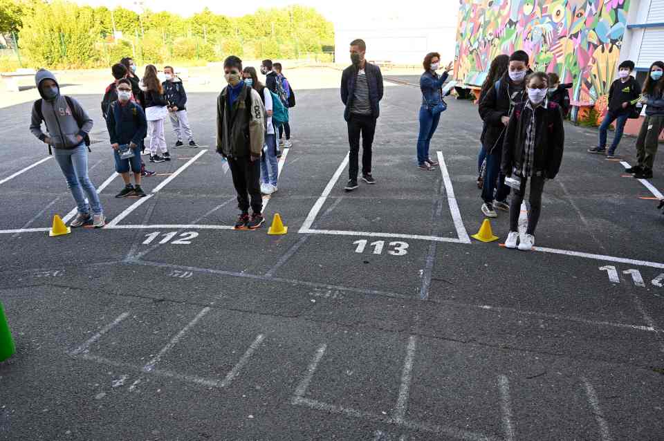  Schoolchildren wearing protective face masks line up before entering Claude Debussy college in France