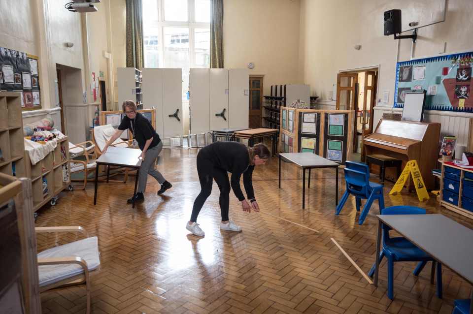  Head teacher Frances Swallow (L) and Teaching Assistant Sarah Yates (R) work to covert the assembly and dining hall into a classroom with separated seating