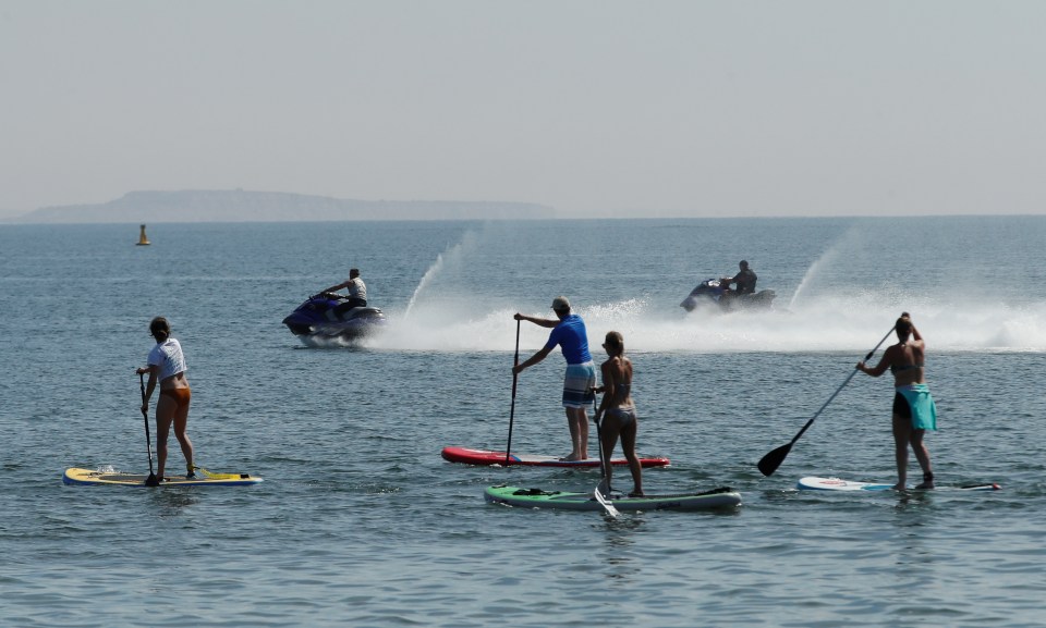  People are seen jet-skiing and paddleboarding at Sandbanks Beach