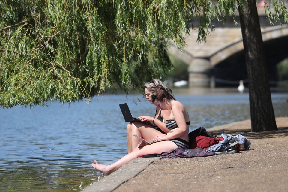  Two women keep cool in the hot weather at the Serpentine in Hyde Park