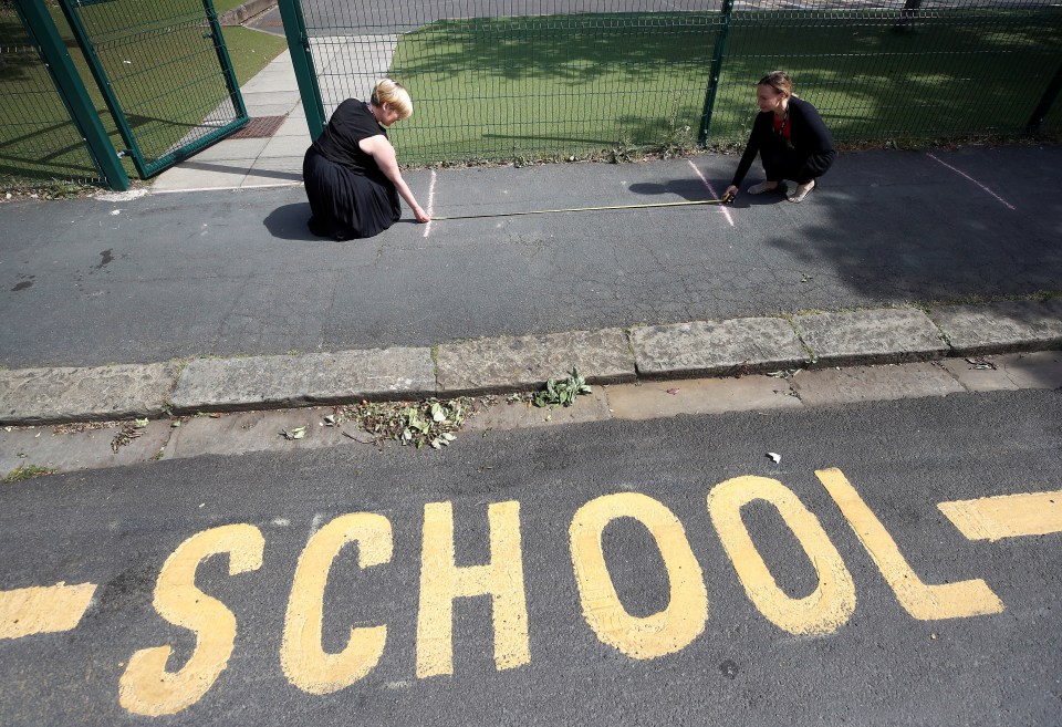  Staff at St Margarets measure the markings for children to queue outside the school