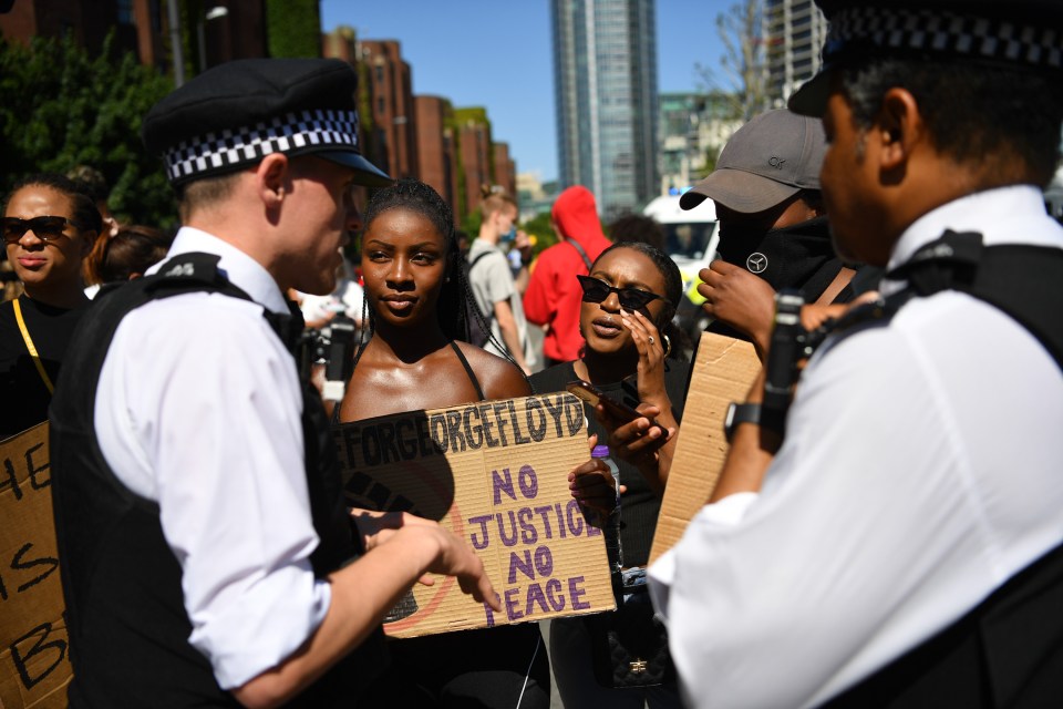 Two women hold a banner reading ‘no justice, no peace’