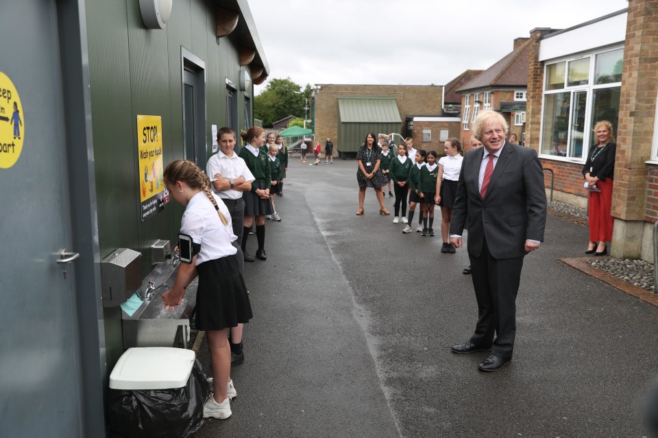 Prime Minister Boris Johnson waits in line in the playground to wash his hands during a visit to Bovingdon Primary School in Bovingdon, Hemel Hempstead, Hertfordshire