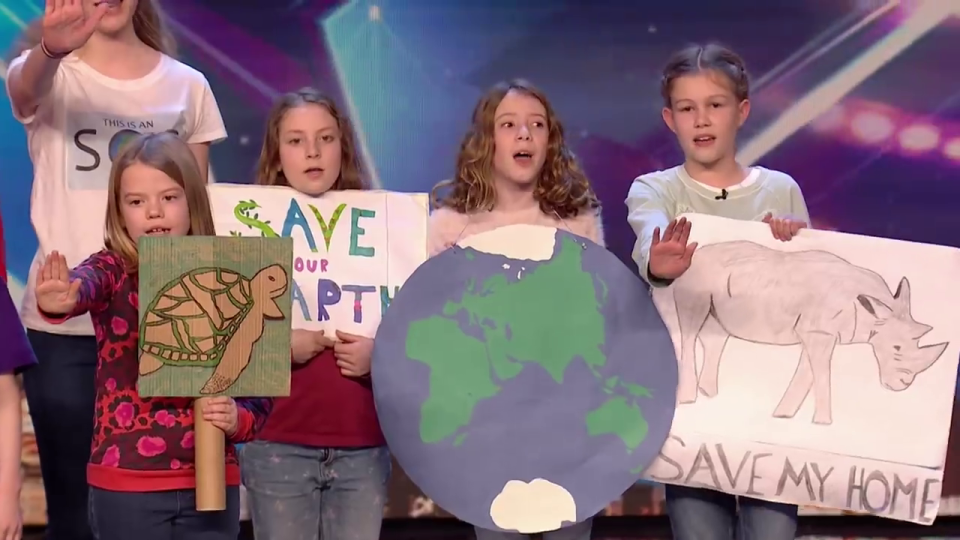  The children sing and hold up placards and posters about saving the planet