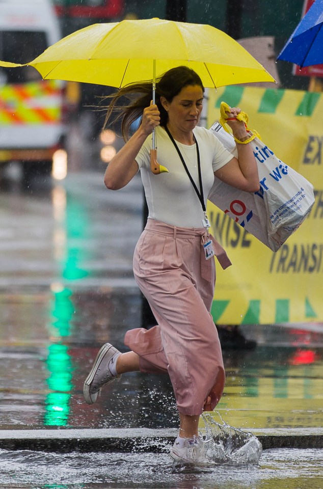  One woman dodges torrential rainfall at London's Parliament Square in Westminster