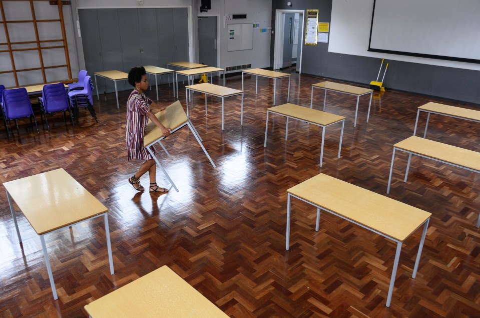 A teacher carries as desk at Muswell Hill Primary School in London ahead of reopening earlier this month