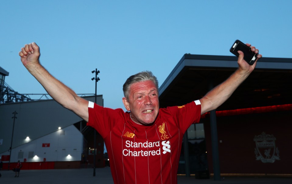 A Liverpool holds his arms aloft outside Anfield 