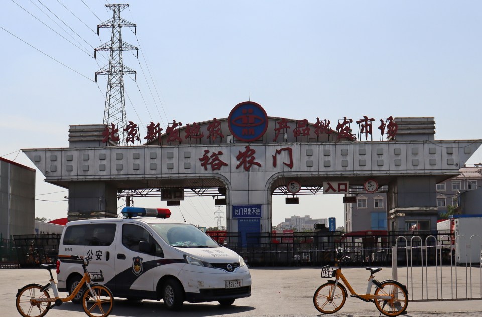 A police car monitors the entrance to the Xinfadi wholesale market