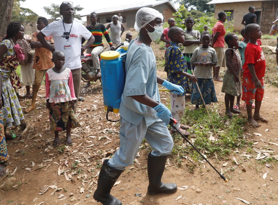  A healthcare worker sprays an area around the house of a man suspected to be infected with Ebola