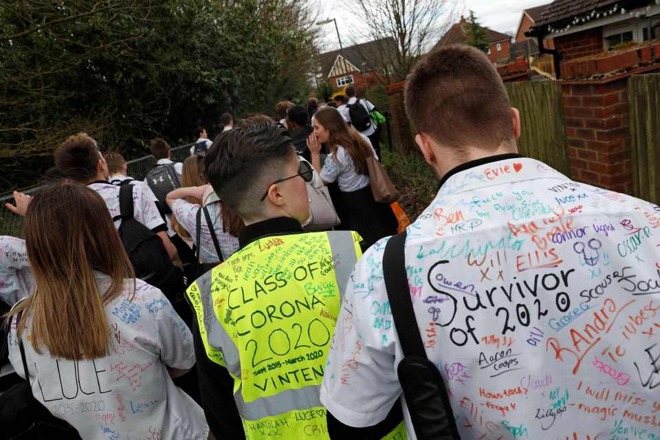  Year 11 pupils, some with graffiti-covered shirts reading 'Survivor 2020' and 'Class of Corona 2020' react as they leave a secondary school in Odiham, west of London on March 20