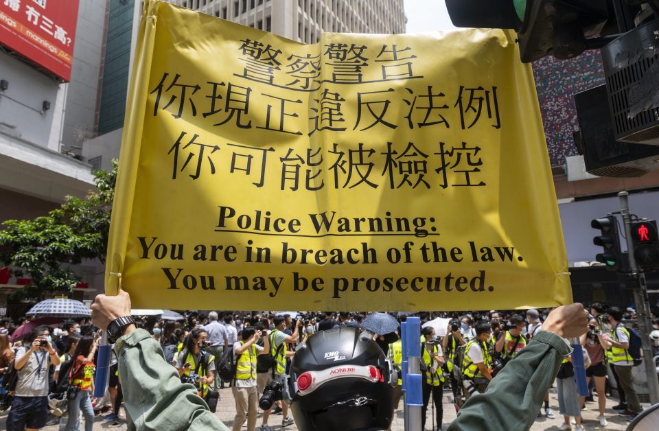  A police officer in Hong Kong holds a yellow banner warning the public they'll be prosecuted if they continue to gather