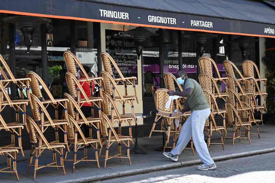 A barman prepares the terrace of a restaurant in Paris