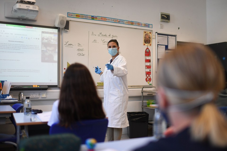  A teacher wearing a face mask teaches Year 6 pupils in a classroom with other pupils participating by video conference at the College Francais Bilingue De Londres French-English bilingual school in north London on June 2