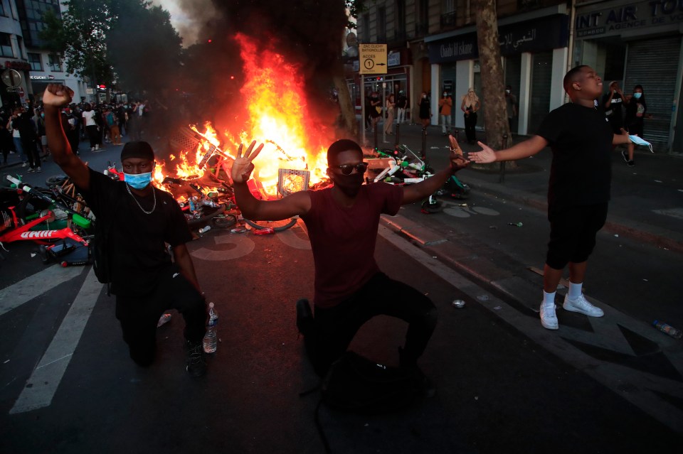  A group of Parisian protesters knelt to the ground as a street fire raged behind them