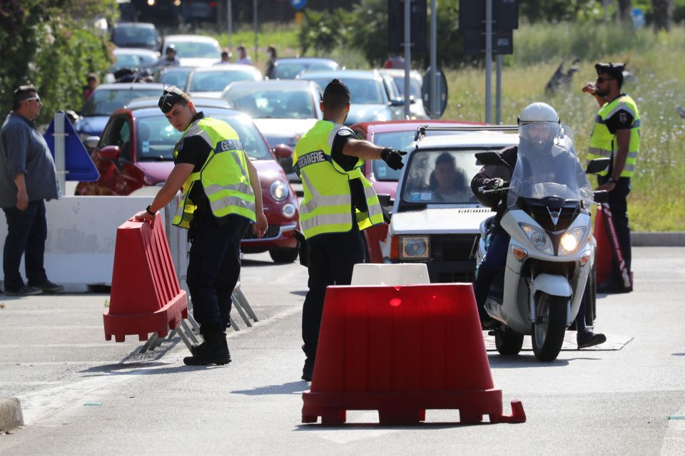  Travellers drive past French gendarmes as they cross the French-Italian border near Menton