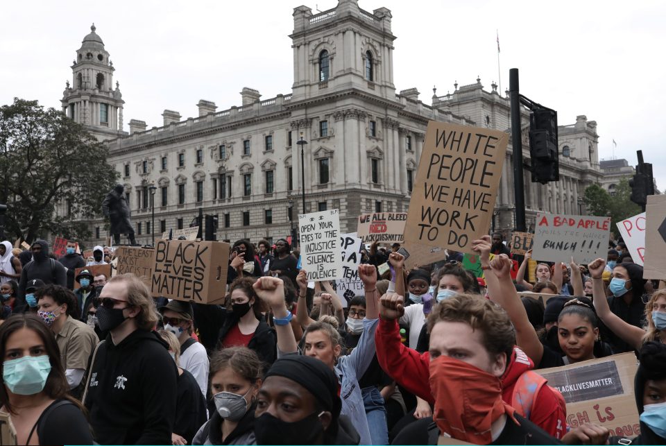  Protesters wearing face masks, hold up placards and raise clenched fists during a Black Lives Matter protest outside the Houses of Parliament on Wednesday