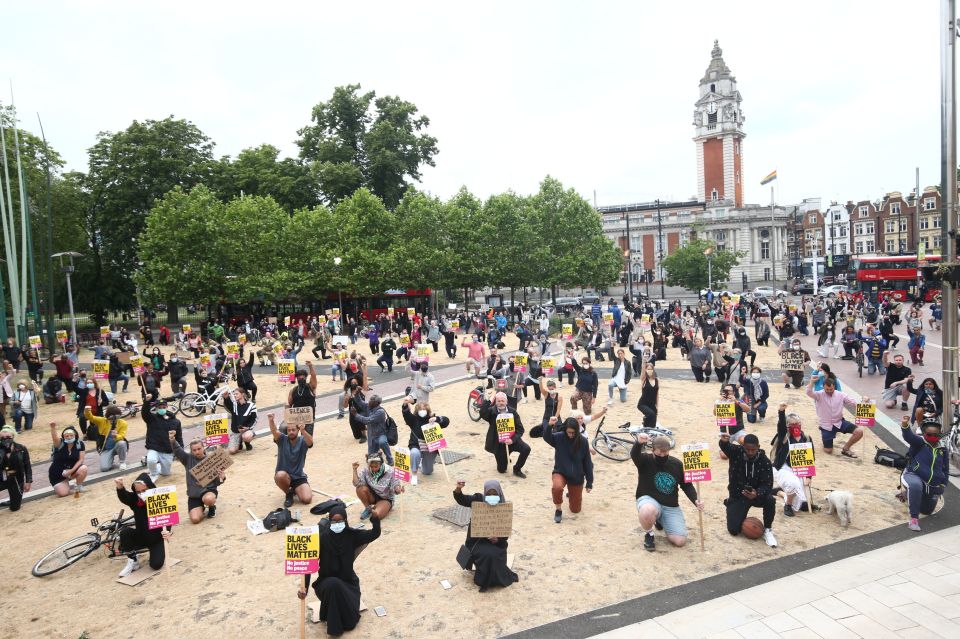 People take a knee during a Black Lives Matter protest rally at Windrush Square, Brixton, south, London