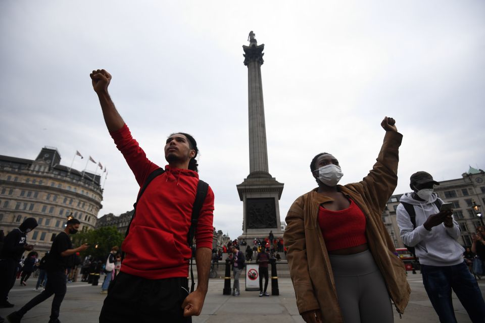 People salute by Nelson's Column as they gather for a minute's silence at a Justice for Black Lives protest at Trafalgar Square in London, June 3