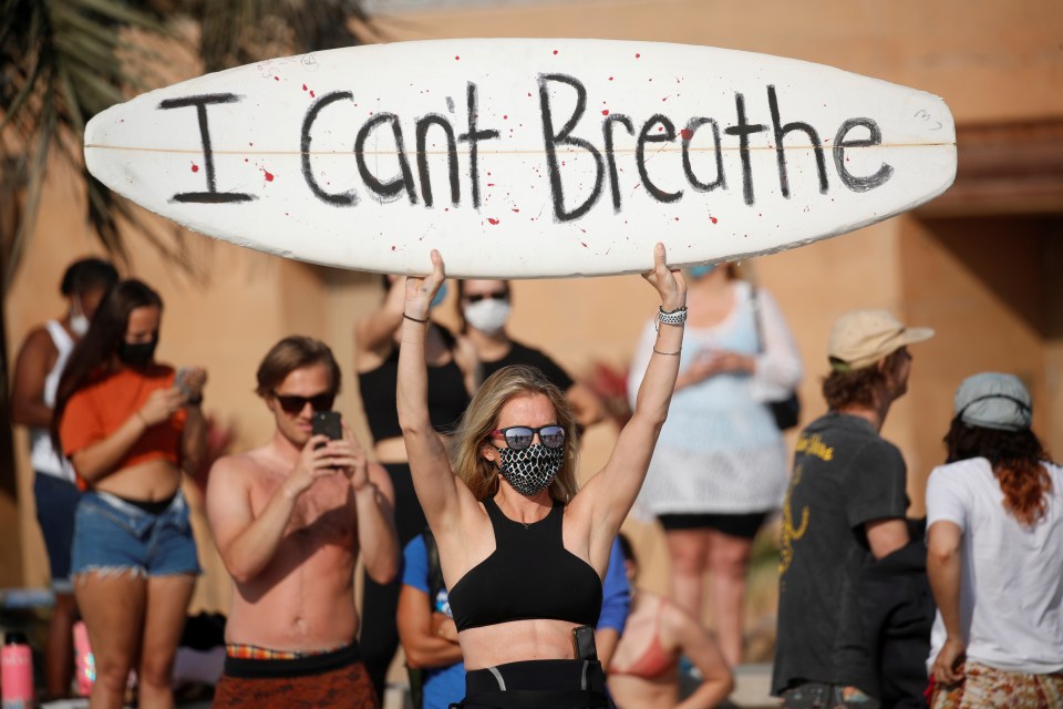 A protester holds up a sign showing George Floyd's last words