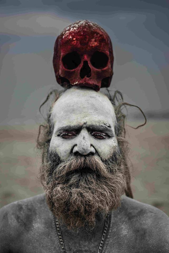  A red-stained skull sits atop the head of an Aghori man