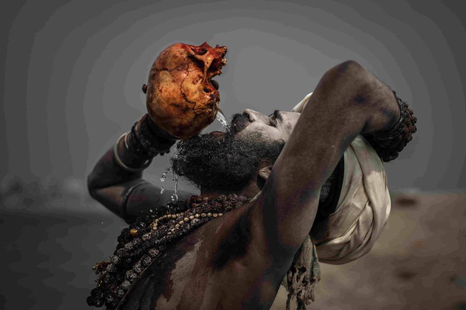  An Aghori man drinks from a bloodied human skull