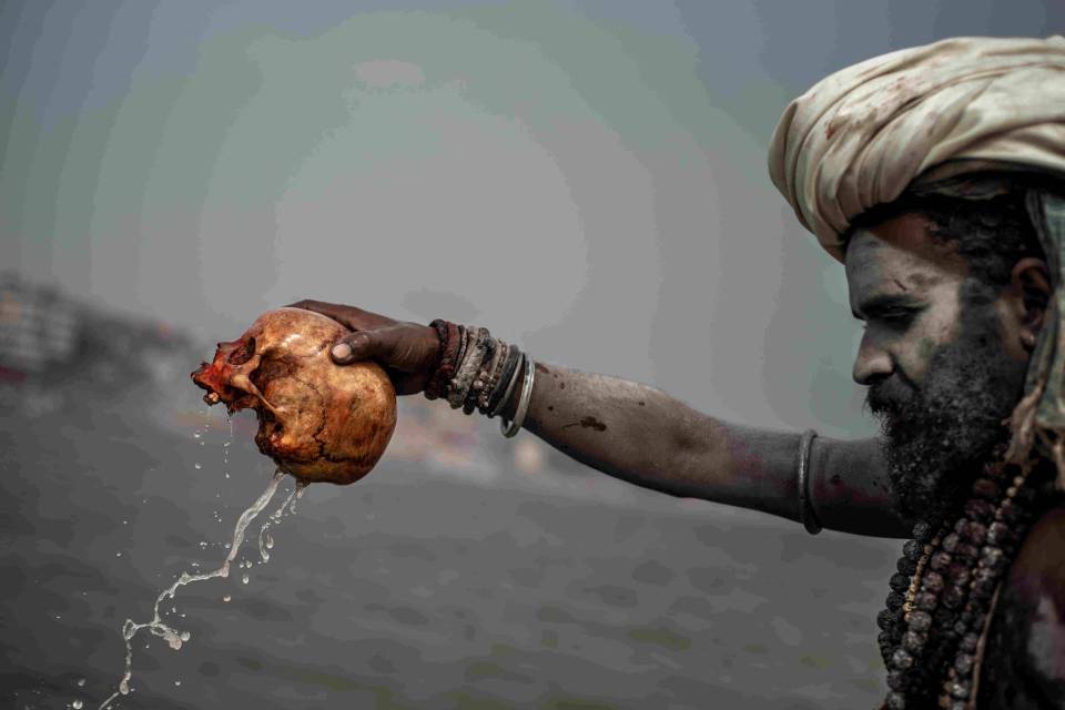  An Aghori man pours water from a human skull