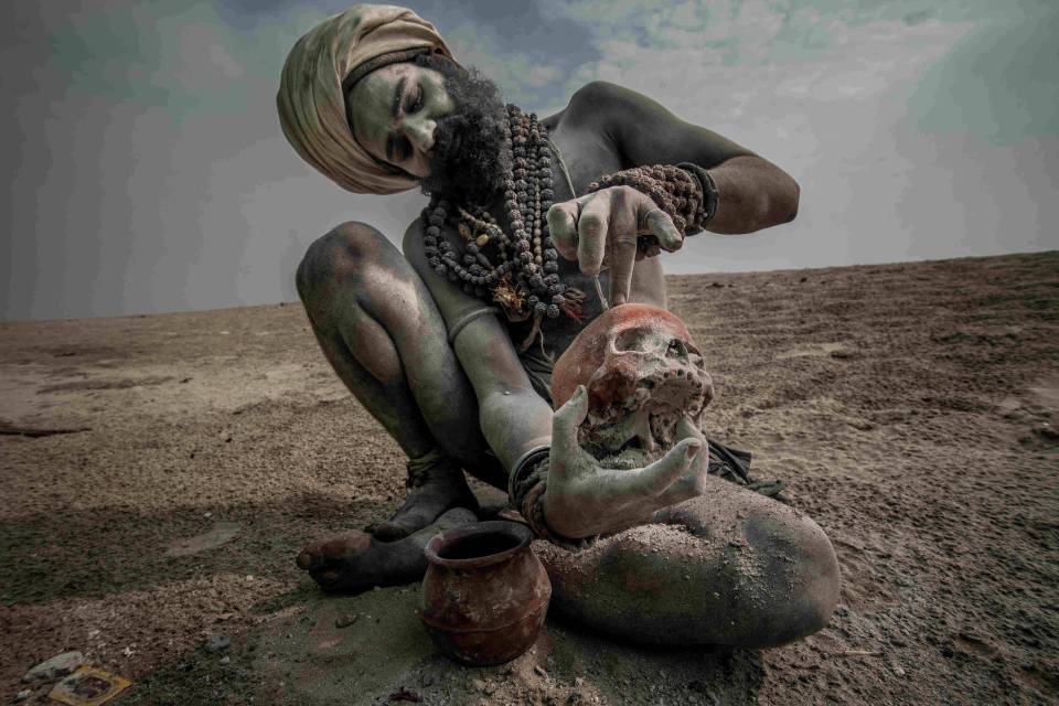  An Aghori man uses ash to cover himself and a human skull