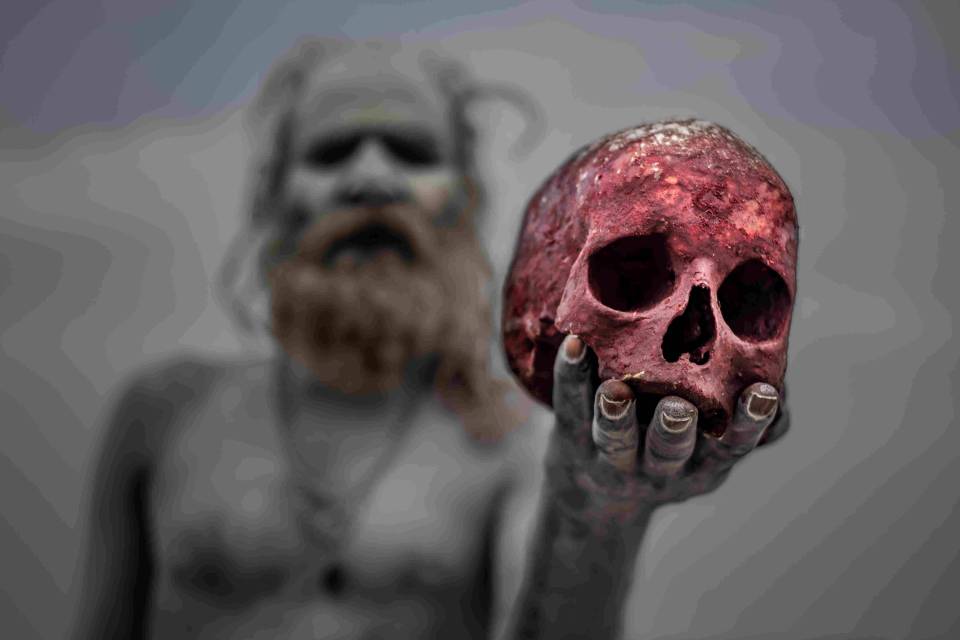  An Aghori man is pictured holding a human skull, which is stained red