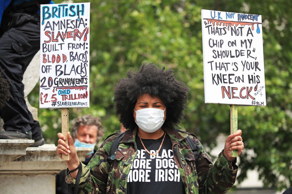 A woman in Manchester holds two signs as she protests for Black Lives Matter in Manchester