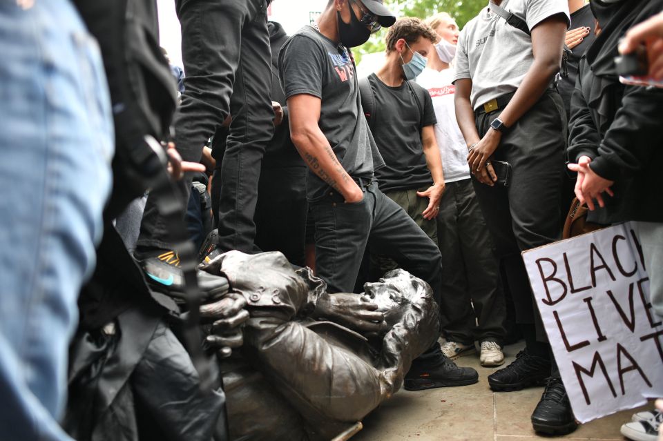 A protester kneels on the statues neck in scenes similar to the death of George Floyd