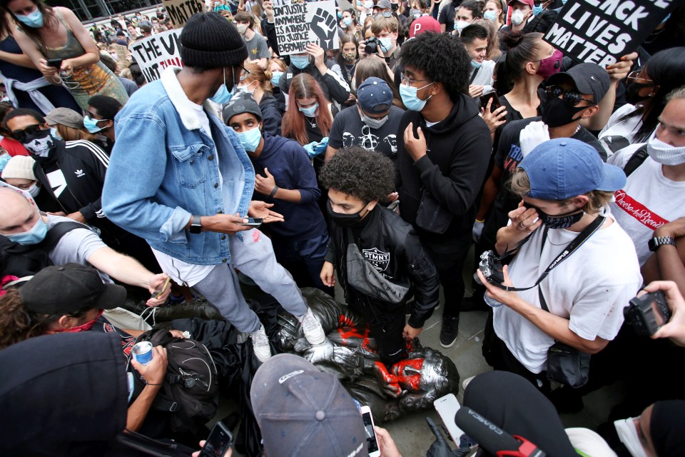  A protester stands on the toppled statue