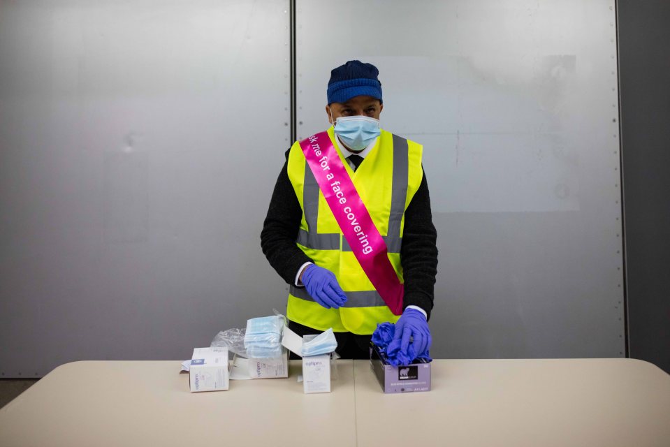 A transport worker is ready to hand out face masks at a Tube station