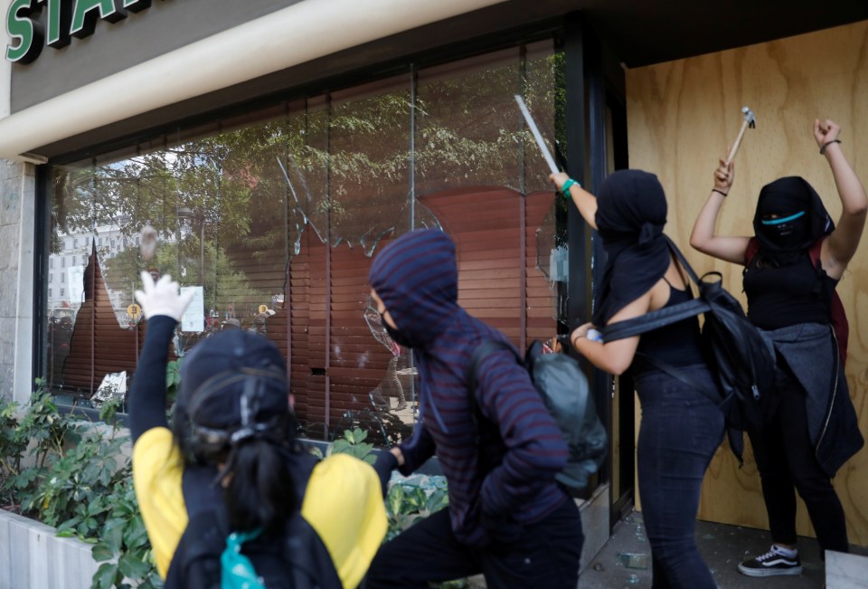 Protesters carrying hammers smash shopfront windows